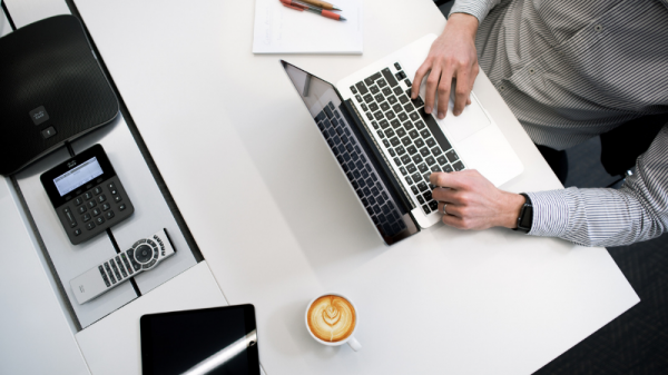 Man in striped shirt working on laptop near coffee