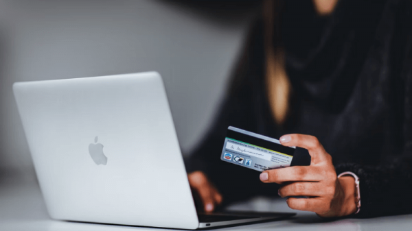 Woman with laptop holds card