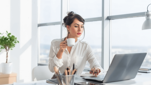 Woman working on laptop while drinking coffee