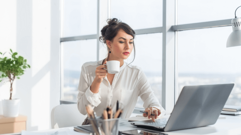 Woman working on laptop while drinking coffee